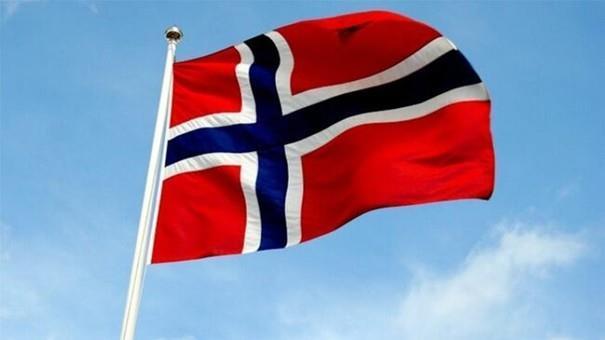 Norsk flagg som vaier i vinden med blå himmel bak